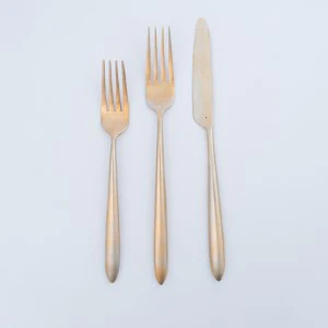 Three minimalist light wood utensils: fork and two knives on white background.