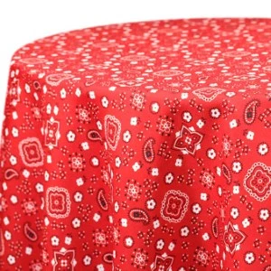 Red bandana-print tablecloth with white floral and paisley design for rustic event rentals.