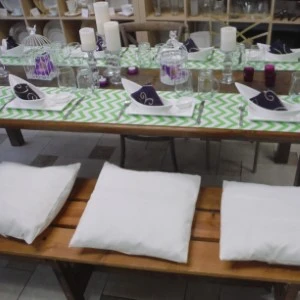 White table with green chevron runner, purple accents, and three white cushions on wooden bench.