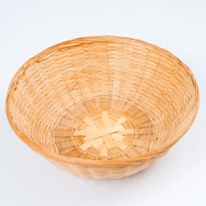 Woven round basket in light golden wicker with intricate radial weave pattern and wide circular shape.