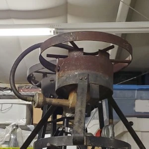 Rusty vintage industrial metal wheel mechanism with curved spokes and mounting bracket.
