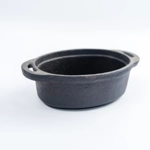 Oval cast iron Dutch oven with dark gray finish and sturdy side handles.