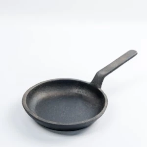 Black cast iron skillet with long handle, featuring a smooth non-stick cooking surface.