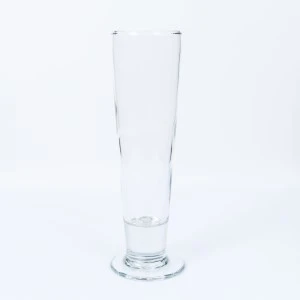 Tall, transparent glass tumbler with thick base, clear and empty, against white background.
