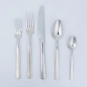 Polished silver flatware set with five utensils arranged vertically on light blue background.