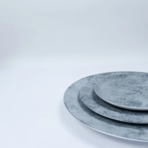 Stacked gray ceramic plates with distressed, matte finish for minimalist event tableware.