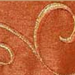 Terracotta fabric with shimmering gold embroidered curving scroll pattern and textured surface.