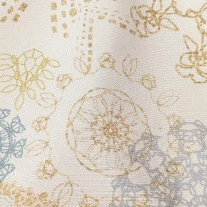 Soft white fabric with delicate gold and blue floral stamp pattern for elegant event linen rental.