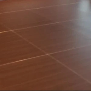 Smooth wooden laminate flooring with diagonal linear patterns in warm brown tones.