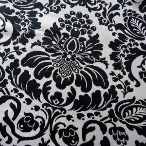 Black and white damask fabric with intricate floral and scrollwork pattern for event linens.