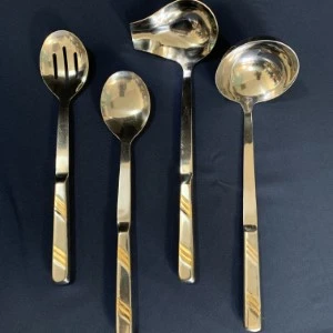 Stainless steel serving utensils with gold-accented handles, including slotted spoon, ladle, and serving spoons.