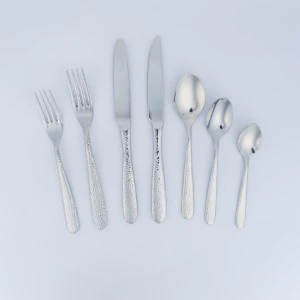 Stainless steel cutlery set with various utensils arranged in ascending size order on light background.