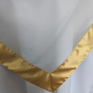 White linen napkin with golden metallic trim folded at crisp corner edge.