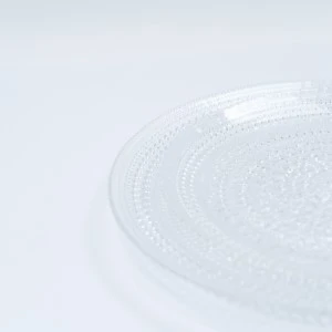 Soft white textured glass or porcelain plate with delicate circular pattern and subtle edge detail.