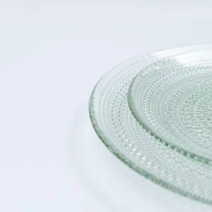 Textured pale green glass plate with delicate raised circular pattern and curved edge.