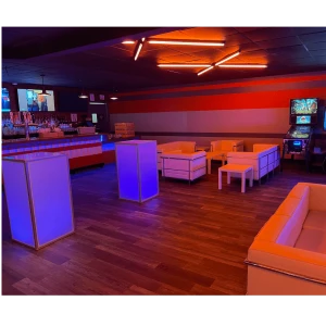 Modern event space with illuminated purple and orange lounge furniture and wood floors.