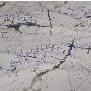 Cracked white marble surface with gray and black intricate veining and textural fissures.