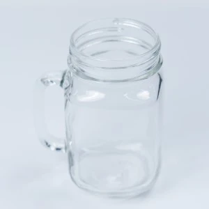 Clear glass Mason jar with handle, transparent and smooth for rustic event beverage service.