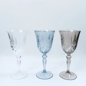 Three vintage crystal wine goblets in white, blue, and gray with cut glass patterns.