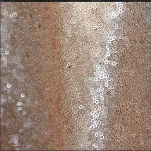 Shimmering sequin fabric in bronze and ivory with textured, circular pattern for event decor.