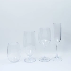 Four clear glass champagne flutes in graduated sizes on a light background.
