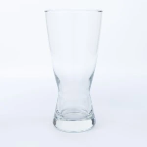 Clear glass pilsner beer tumbler with tapered shape and thick base on white background.