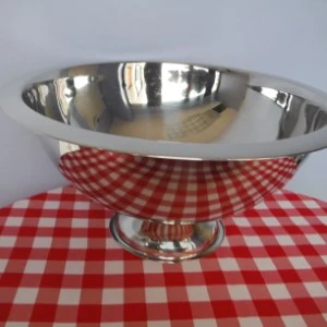 Stainless steel serving bowl on silver pedestal with red and white checkered tablecloth.