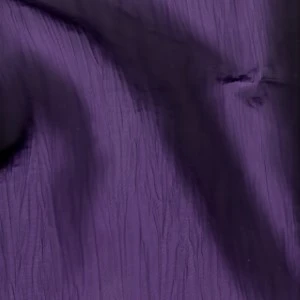 Deep purple crinkled fabric with soft folds and textured vertical ripple effect for event linens.