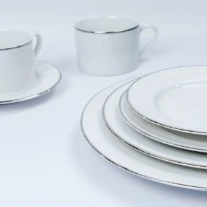 White porcelain dinnerware set with silver platinum rim, featuring stacked plates and delicate coffee cup.