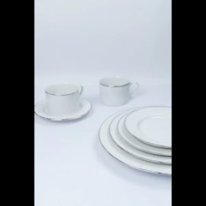 White porcelain dinnerware set with stacked plates, cup, and saucer on minimalist background.
