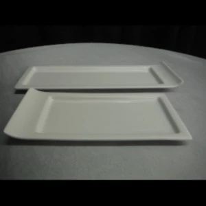 Two rectangular white ceramic serving platters stacked on a neutral surface.