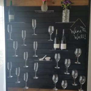 Black wooden wine wall display with 20 clear wine and champagne glasses arranged artfully.