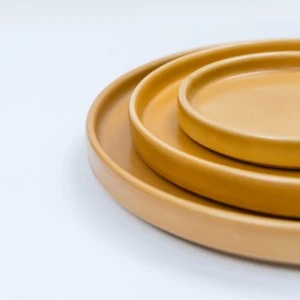 Mustard yellow ceramic plates stacked with smooth, matte finish and minimal design.