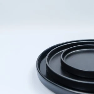 Sleek black stacked serving platters with smooth round edges on minimalist white background.