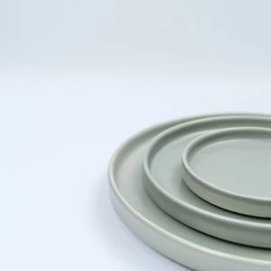 Stacked sage green ceramic plates with minimalist round design and subtle texture.