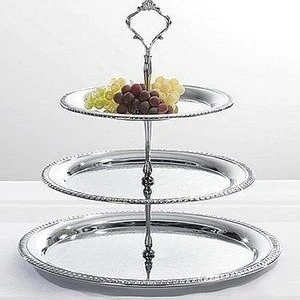 Three-tier silver serving stand with decorative edge, displaying green and purple grapes on top.