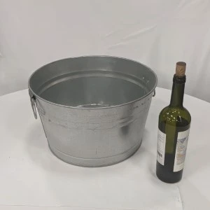 Metallic galvanized steel bucket and green wine bottle on white background for event styling.