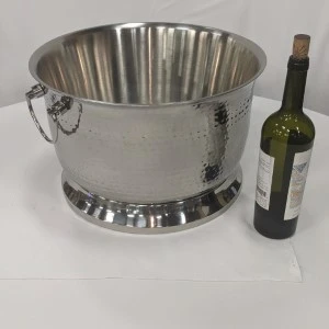 Hammered stainless steel wine cooler bucket with side handles and wine bottle for scale.