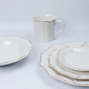Delicate white porcelain dinnerware set with subtle gold trim and scalloped edges.