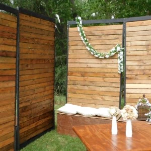 Wooden privacy fence with modern design frames minimalist wedding arch and white bench.