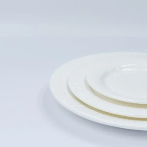 Three stacked white ceramic dinner plates with smooth glazed surface on light background.
