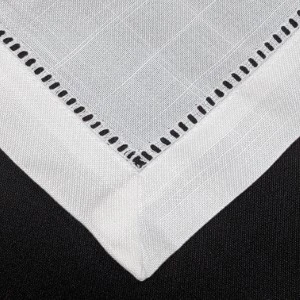 White linen napkin with decorative hemstitched border and geometric cutwork detail.