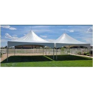 White peaked event tent with double peaked fabric roof on green lawn with blue sky backdrop.