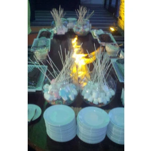 White fabric table linens surround glowing centerpiece with wheat grass and soft lighting for elegant event decor.