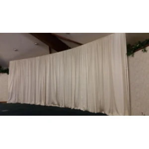 Large white floor-length fabric drape covering event backdrop with soft, flowing pleated texture.