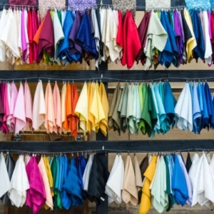 Swatches of fabric in different colors hang clipped to a line above in three different rows.