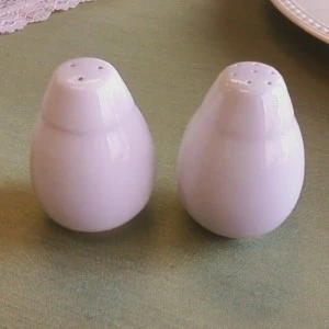 Two soft pink ceramic salt and pepper shakers with rounded teardrop shapes on a neutral surface.