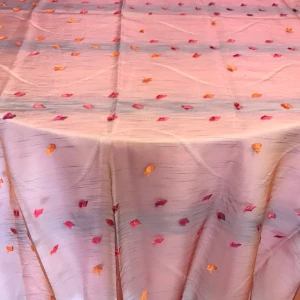 Elegant translucent rose colored tablecloth with darker pink metallic accents drapes over a table