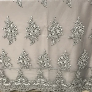 Silver beaded lace fabric with intricate floral embroidery and scalloped border for elegant event decor.